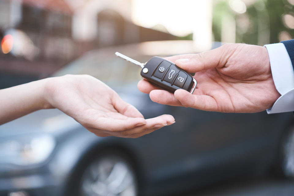 A person hands off a car key to another person.