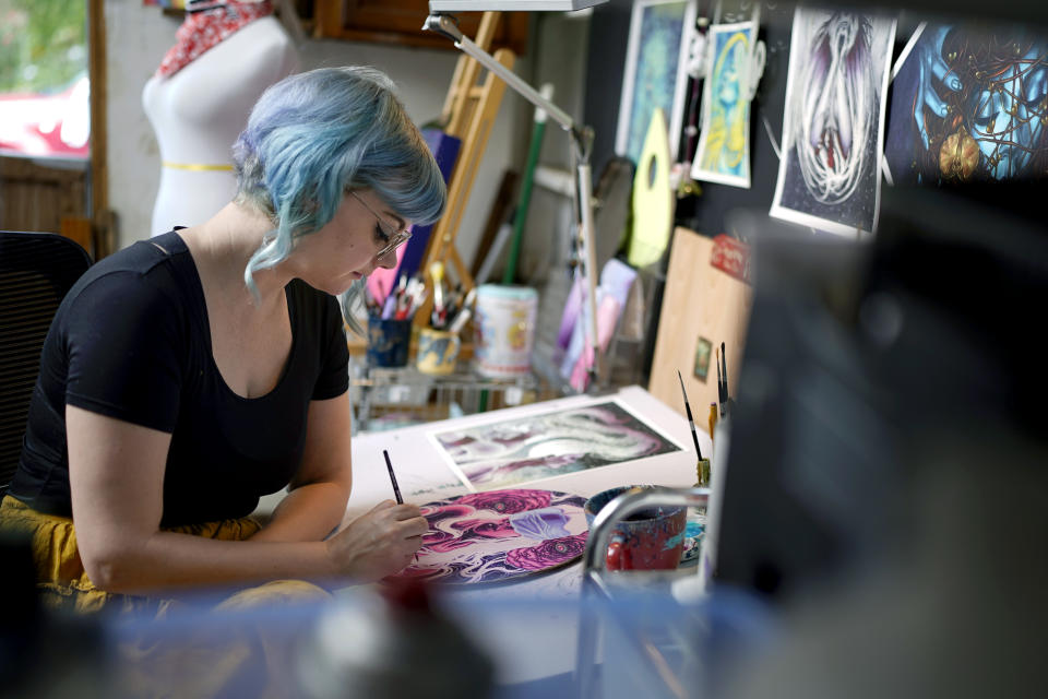 Artist Kelly McKernan paints in their studio Tuesday, Aug. 15, 2023, in Nashville, Tenn. McKernan is an artist and one of three plaintiffs in a lawsuit against artificial intelligence companies they allege have infringed on their copyright. (AP Photo/George Walker IV)