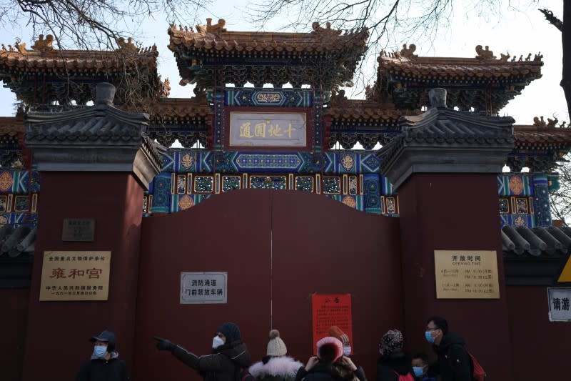 People stand in front of the closed gate of Lama Temple, with a notice saying that the temple is closed for safety concerns following the outbreak of a new coronavirus on its gate, in Beijing