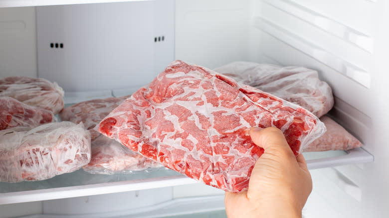 hand pulling frozen meat out of freezer