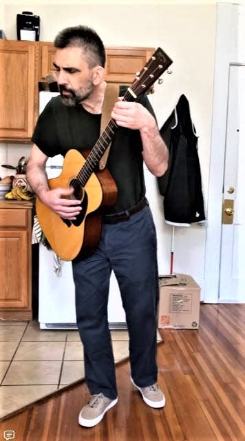 Rafe Sweeney plays the guitar in his apartment in North Carolina.