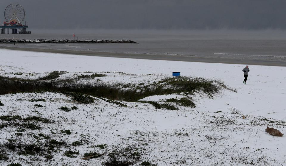 A jogger runs along a snow-covered beach on Monday in Galveston, Texas.