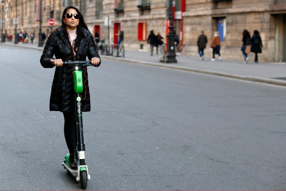 A woman rides an electric scooter she rented from the bike sharing service company 'Lime' in Paris - Getty Images