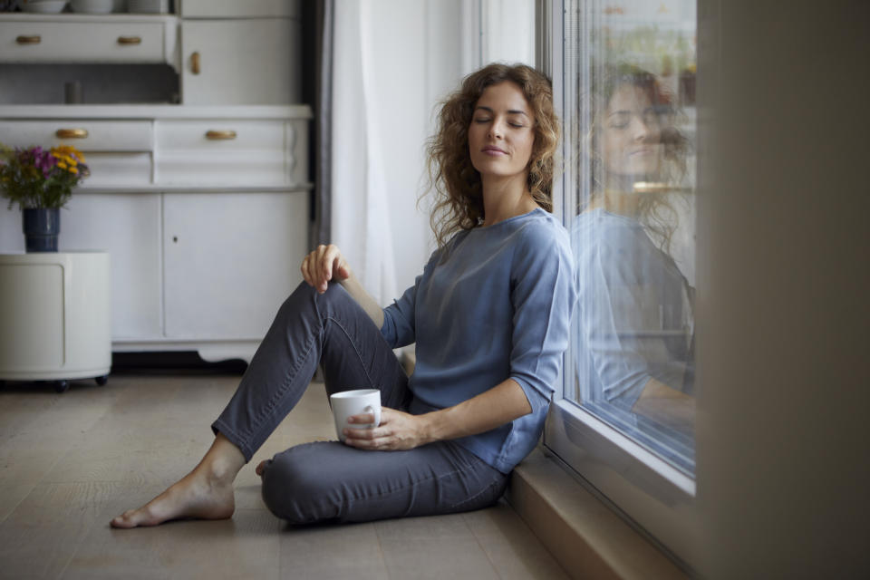 A woman sitting by her window with a coffee mug in her hand