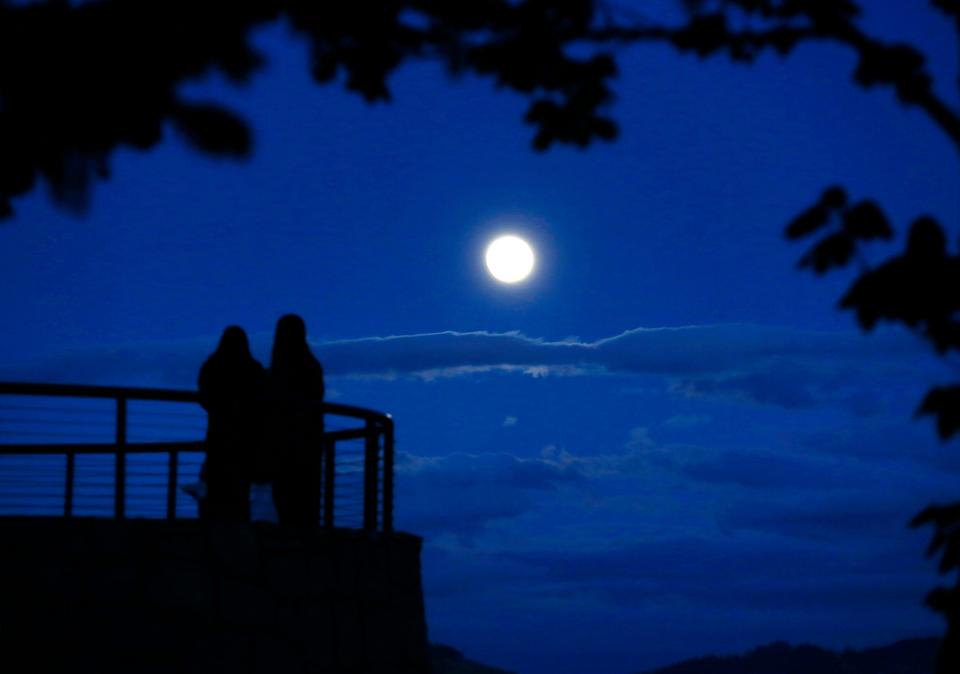 People gather on the overlook at Skinner Butte in Eugene to watch the Super Pink Moon rise over the Willamette Valley Monday in April 2021.