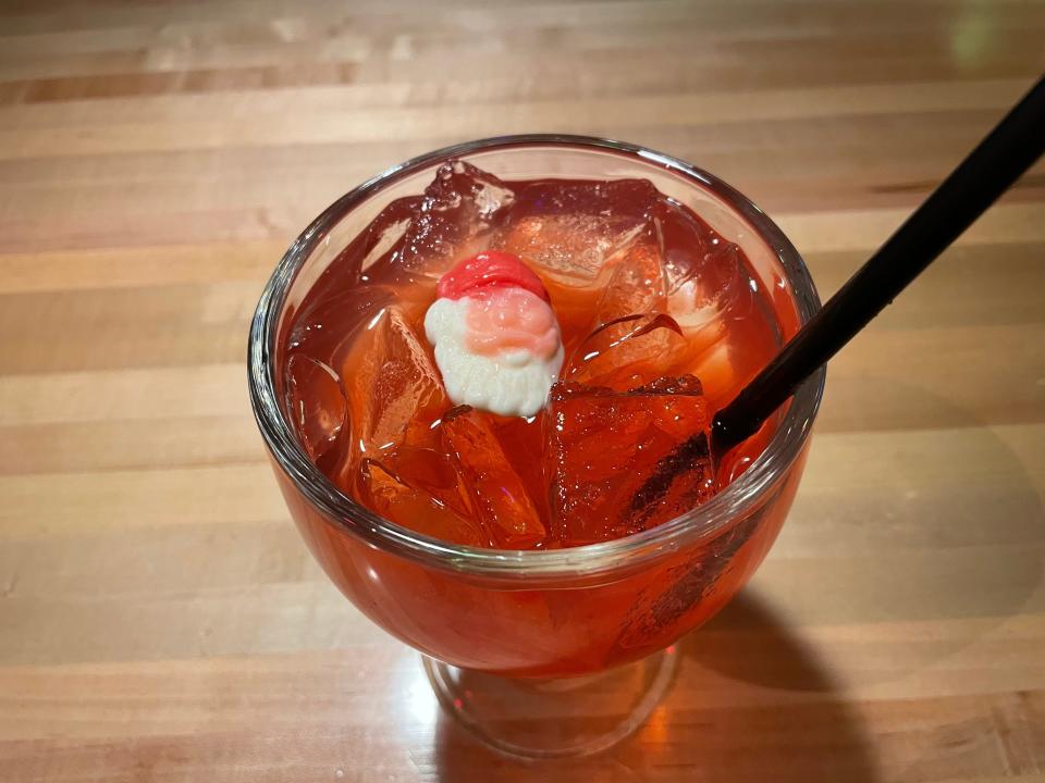 A red cocktail with a Santa head candy floating on top