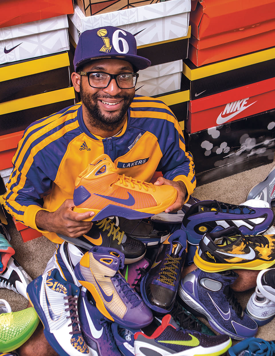 Sneaker collector Darryl Glover, dressed in Lakers colors, sits among a large pile of Kobe Bryant Nike shoes that he has amassed over the years.