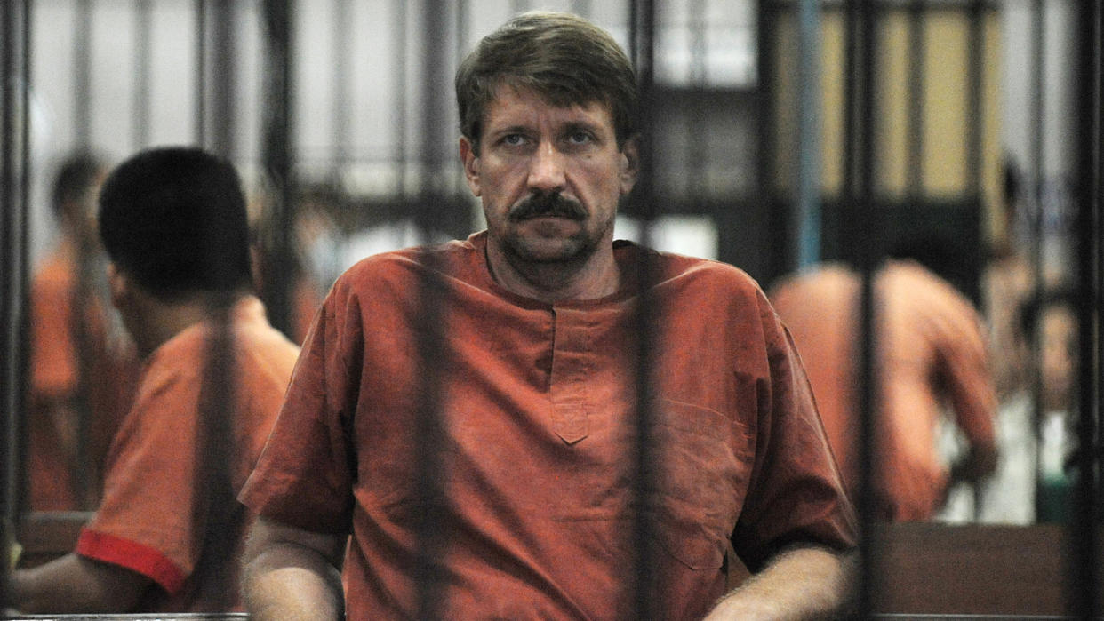 Viktor Bout in orange shirt behind bars.