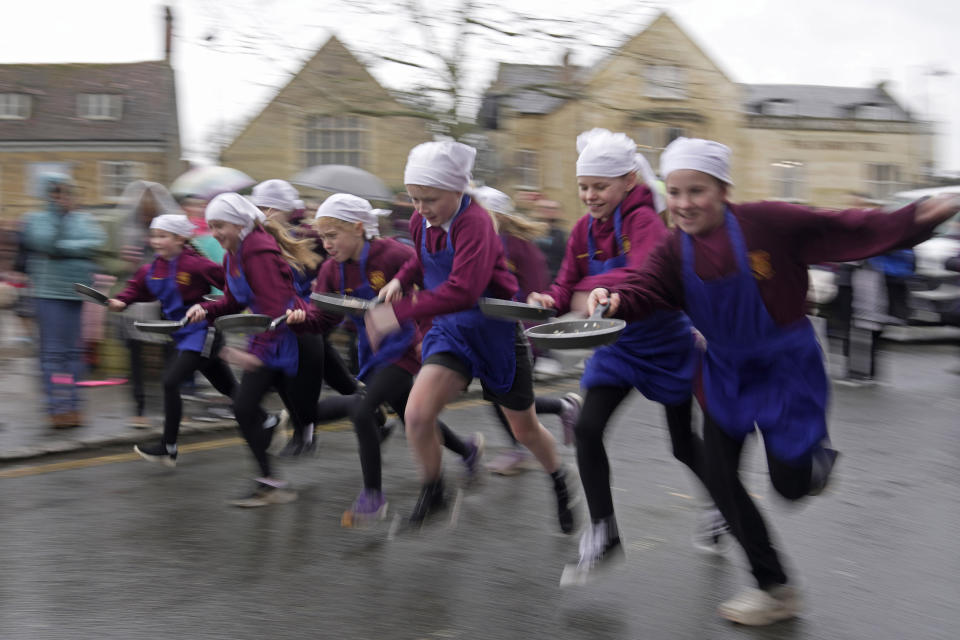 Schoolchildren from local schools take part in the children's races prior to the annual Pancake race in the town of Olney, in Buckinghamshire, England, Tuesday, Feb. 13, 2024. Every year women clad in aprons and head scarves from Olney and the city of Liberal, in Kansas, USA, run their respective legs of the race with pancakes in their pans. According to legend, the Olney race started in 1445 when a harried housewife arrived at church on Shrove Tuesday still clutching her frying pan with a pancake in it. (AP Photo/Kin Cheung)