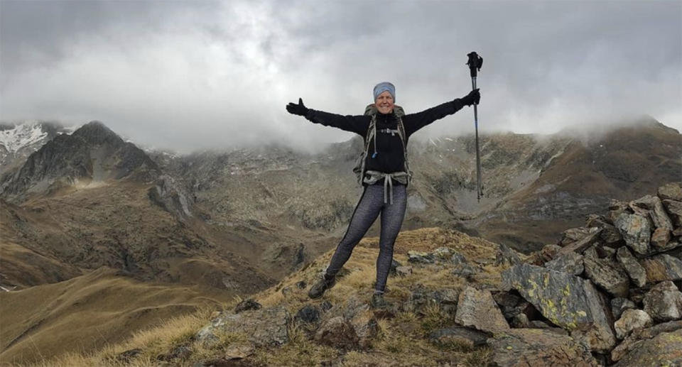 Esther Dingley poses for a photo on top of a mountain range