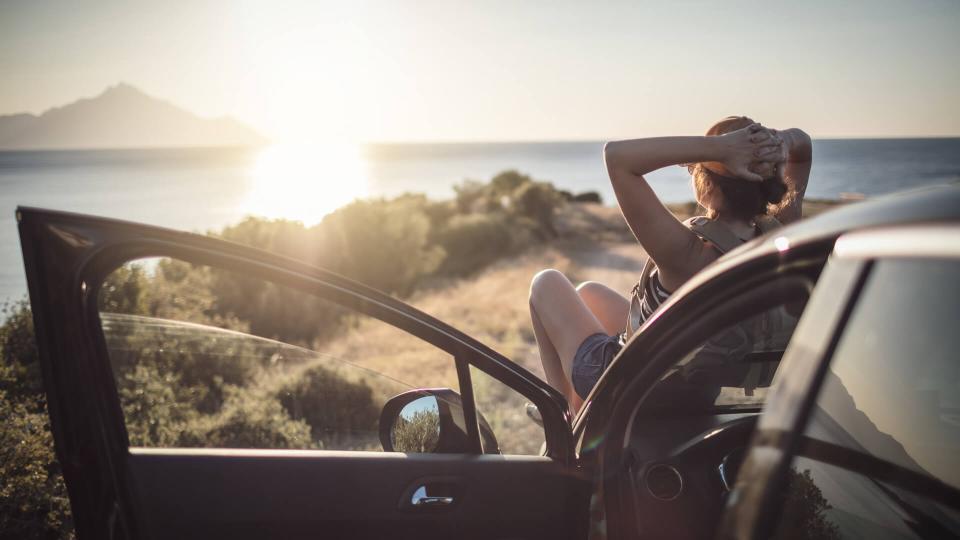 Woman relaxing on her car at the road trip.