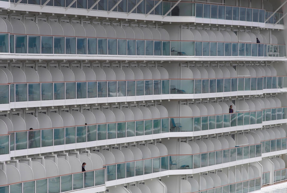 Passengers are seen on the World Dream cruise ship docked at Kai Tak cruise terminal in Hong Kong, Wednesday, Feb. 5, 2020. A Hong Kong official says more than 3,600 people on board the cruise ship that was turned away from a Taiwanese port will be quarantined until they are checked for a new virus. (AP Photo/Vincent Yu)