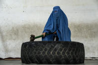 An Afghan woman who practices jiujitsu, a Japanese martial art, poses with a sledgehammer she uses for strength exercises in Kabul, Afghanistan, Sunday, Nov. 6, 2022. The ruling Taliban have banned women from sports as well as barring them from most schooling and many realms of work. A number of women posed for an AP photographer for portraits with the equipment of the sports they loved. Though they do not necessarily wear the burqa in regular life, they chose to hide their identities with their burqas because they fear Taliban reprisals and because some of them continue to practice their sports in secret. (AP Photo/Ebrahim Noroozi)