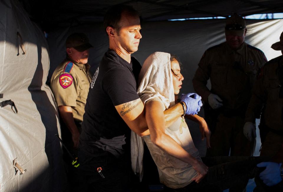 美國德州伊格帕斯市（Eagle Pass）救護人員26日將一名熱衰竭的申請庇護婦女放上擔架，準備送醫。路透社