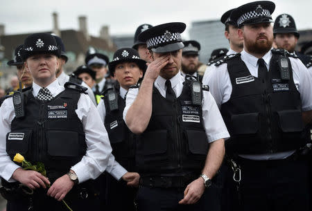 A Police officer wipes his face as one of his colleagues holds a rose during an event to mark one week since a man drove his car into pedestrians on Westminster Bridge then stabbed a police officer in London, Britain March 29, 2017. REUTERS/Hannah McKay