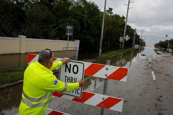 A worker posts a sign to prevent traffic from going through a flooded street after Hurricane Nicole's landfall at Vero Beach, Florida, on November 10, 2022. - Tropical Storm Nicole slowed after making landfall in the US state of Florida, meteorologists said Thursday. (Photo by Eva Marie UZCATEGUI / AFP) (Photo by EVA MARIE UZCATEGUI/AFP via Getty Images)