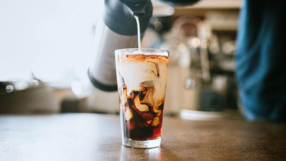 Milk being poured into a glass of coffee, giving a marbled effect