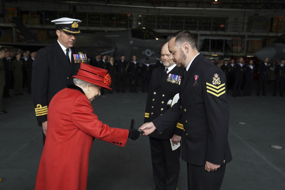 Britain's Queen Elizabeth II presents the 15 years long service and good conduct medal to Petty Officer Matthew Ready, during a visit to the HMS Queen Elizabeth at HM Naval Base, ahead of the ship's maiden deployment, in Portsmouth, England, Saturday May 22, 2021. HMS Queen Elizabeth will be leading a 28-week deployment to the Far East that Prime Minister Boris Johnson has insisted is not confrontational towards China. (Steve Parsons/Pool Photo via AP)