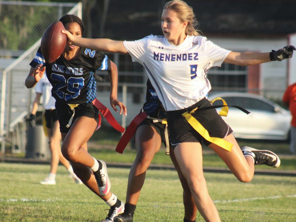 Menendez quarterback Jessie Rot (9) stretches for yardage as Stanton's Laila Cromity (29) and Courtney Brown (26, behind) defend during an FHSAA Region 2-1A high school girls flag football first-round playoff on April 17, 2024. [Clayton Freeman/Florida Times-Union]