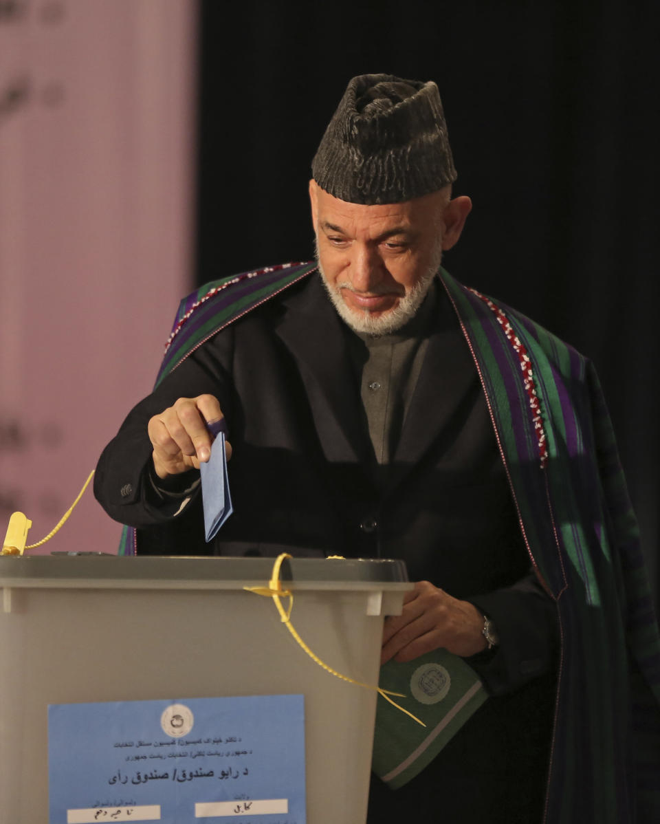 Afghan President Hamid Karzai, right, casts his vote at Amani high school, near the presidential palace in Kabul, Afghanistan, Saturday, April 5, 2014. Afghan voters lined up for blocks at polling stations nationwide on Saturday, defying a threat of violence by the Taliban to cast ballots in what promises to be the nation's first democratic transfer of power. (AP Photo/Massoud Hossaini)