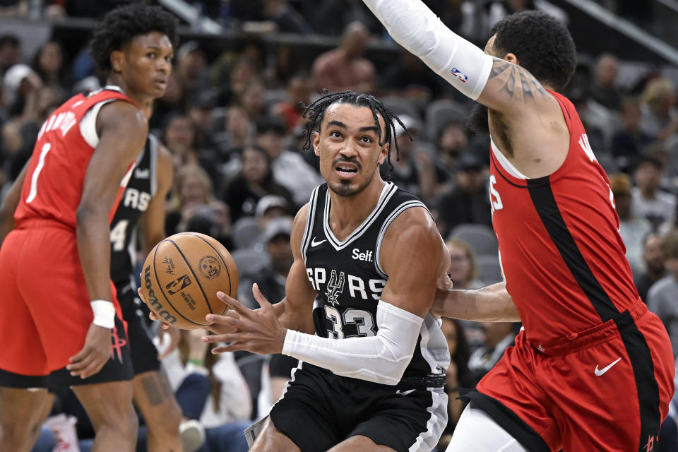 San Antonio Spurs' Tre Jones (33) drives against Houston Rockets' Fred VanVleet, right, during the first half of an NBA basketball game Tuesday, March 12, 2024, in San Antonio. (AP Photo/Darren Abate)