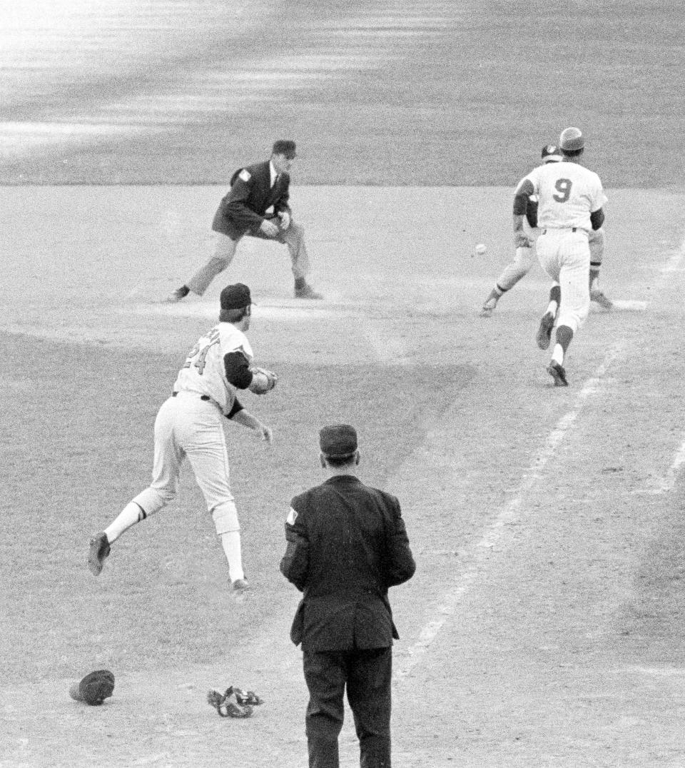 FILE - J.C Martin races for first as Pete Pichert's throw bounds away in the tenth inning of Game 4 of the World Series baseball game in New York's Shea Stadium, Oct. 15, 1969. Martin bunted, Richert picked it up and threw to Dave Johnson covering first. Ball hit Martin in the back. Ump at home is Shag Crawford and first base ump is Lou DiMuro. Major League Baseball is widening the runner's lane approaching first base to include a portion of fair territory, shortening the pitcher's clock with runners on base by two seconds to 18 and further reducing mound visits in an effort to further speed games next season. (AP Photo/File)