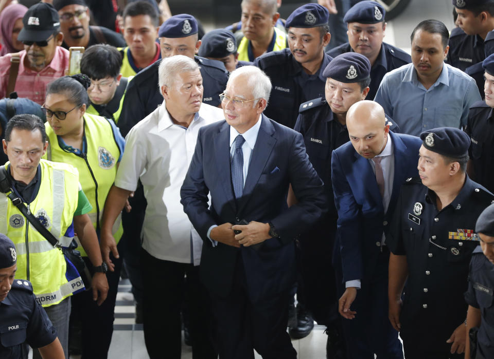 FILE - In this Oct. 4, 2018, file photo, former Malaysian Prime Minister Najib Razak, center, arrives at Kuala Lumpur High Court in Kuala Lumpur, Malaysia. Najib is hardly lying low ahead of his corruption trial set to begin Tuesday, Feb. 12, 2019, on charges related to the multibillion-dollar looting of the 1MDB state investment fund. He’s crooned about slander in an R&B video and vilified the current government on social media to counter portrayals of him as corrupt and out of touch. Najib denies wrongdoing and his lawyers are seeking delay.(AP Photo/Vincent Thian, File)