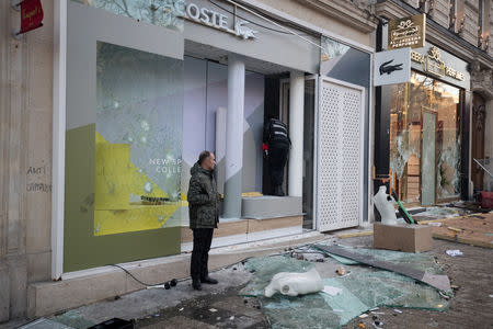 A man stand in front of a damaged shop on the Champs Elysees avenue during a demonstration by the "yellow vests" movement in Paris, France, March 16, 2019. Picture taken March 16, 2019. REUTERS/Philippe Wojazer