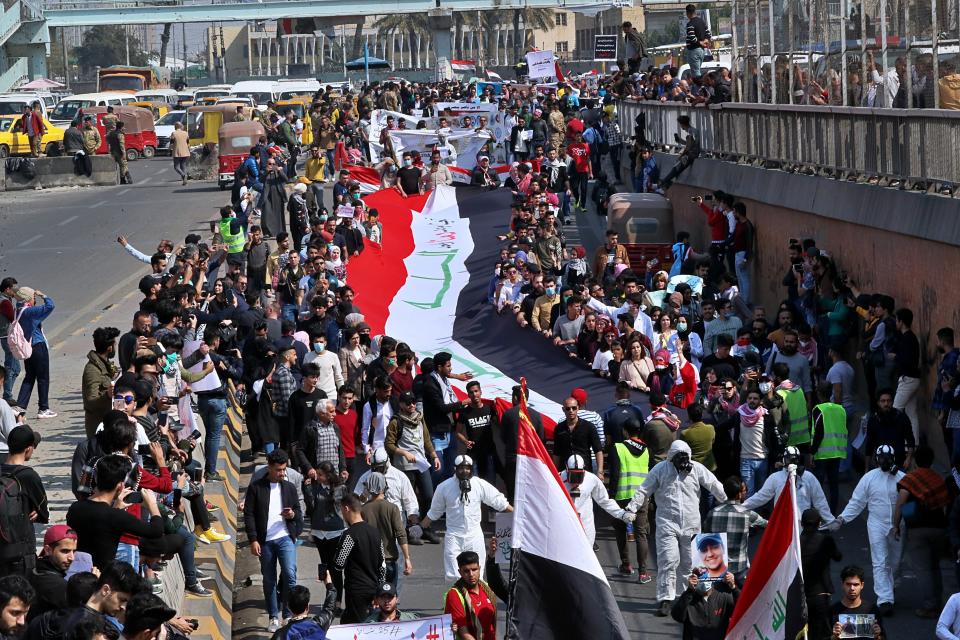 Students and other demonstrators hold national flags during ongoing anti-government protests, in Baghdad, Iraq, Sunday, Feb. 23, 2020. (AP Photo/Khalid Mohammed)