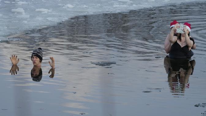 Orang-orang berenang di danau dengan suhu di bawah titik beku di Warsawa, Polandia (26/12/2021). Iklim di Polandia pada musim dingin yang sangat dingin, seringkali di bawah titik beku (0 &#xb0;C atau 32 &#xb0;F), dan musim panas yang hangat.  (AP Photo/Czarek Sokolowski)
