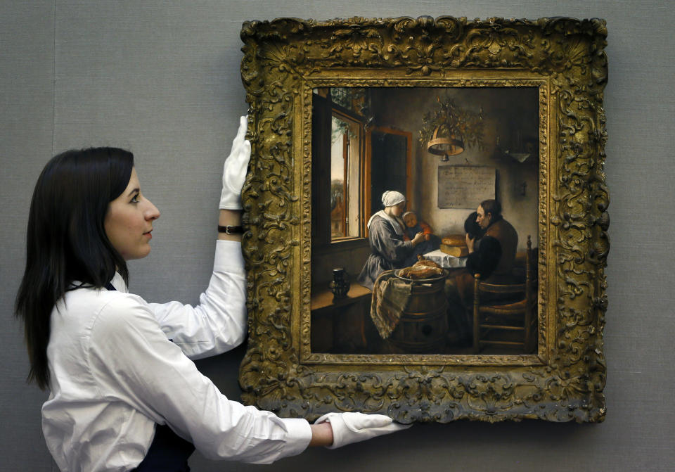 A Sotheby's employee adjusts a painting by Dutch artist Jan Havickszoon Steen called 'The Prayer Before the Meal' during a press viewing in London, Friday, Nov. 30, 2012. The painting estimated at 5-7 million pounds (8-11 million US Dollars) will go on sale in the evening sale of Old Master Paintings and Drawings on Dec. 5 in London. (AP Photo/Kirsty Wigglesworth)