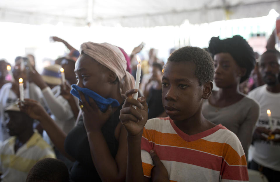 In this Dec. 13, 2018 photo, Wilky Coby, 16, who was shot four times but survived the La Saline massacre, holds up a candle during a memorial for the victims in Port-au-Prince, Haiti. United Nations officials said they expect to complete an investigation into the Nov. 13 La Saline massacre within weeks. (AP Photo/Dieu Nalio Chery)