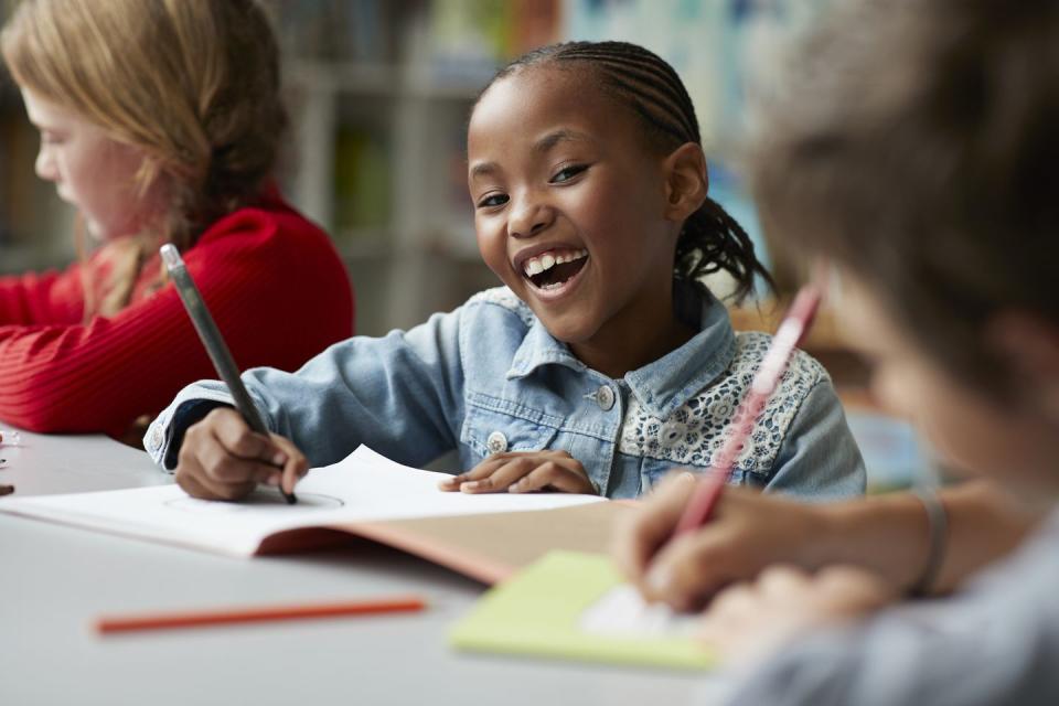 Portrait of schoolgirl drawing at the school library and laughing