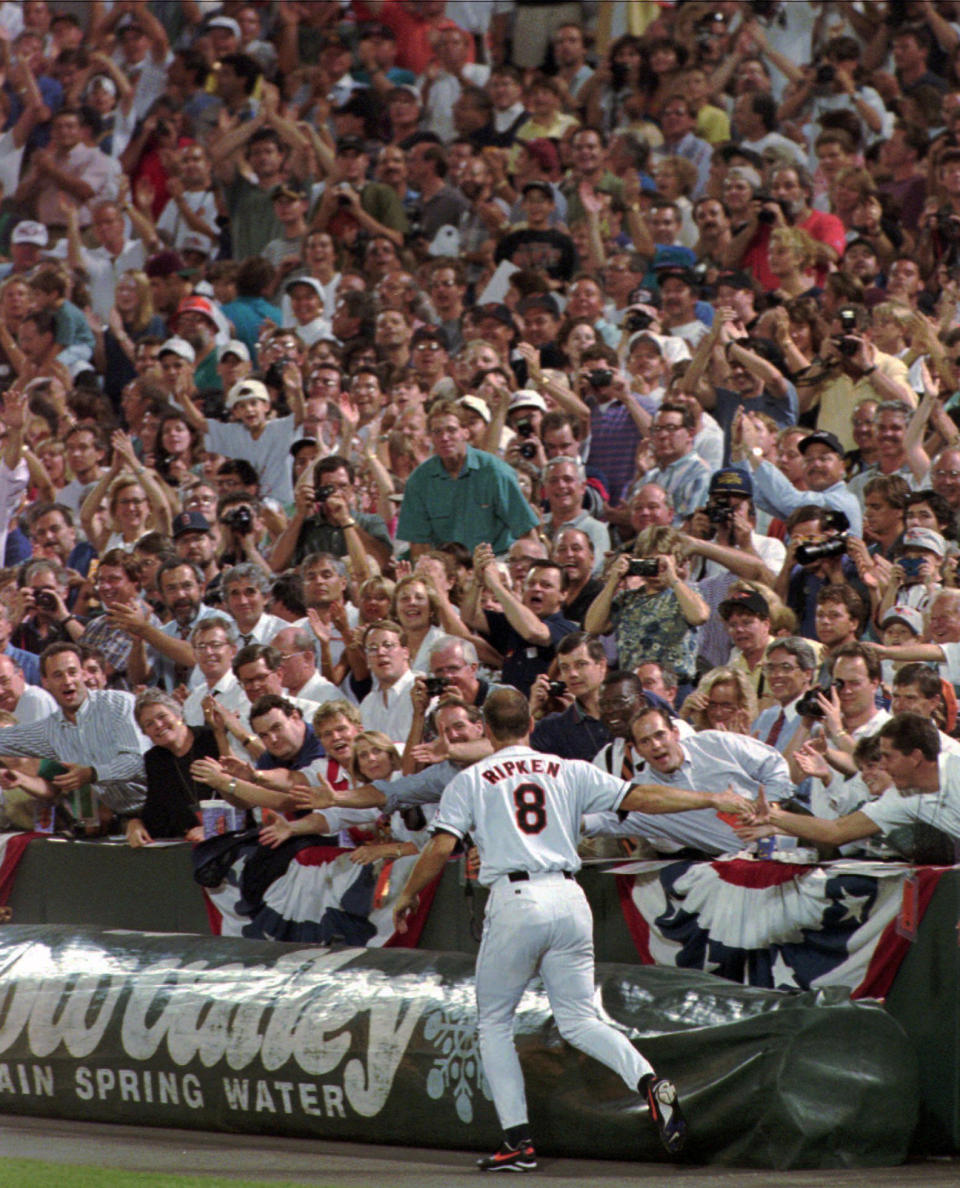 FILE - In this Sept. 6, 1995, file photo, Baltimore Orioles' Cal Ripken Jr. (8) shakes hands with fans as he does a victory lap around Baltimore's Camden Yards after breaking Lou Gehrig's record of 2,130 consecutive games. It has been 25 years since Ripken broke Gehrig's major league record for consecutive games played, a feat the Orioles star punctuated with the unforgettable lap around Camden Yards in the middle of his 2,131st successive start. (AP Photo/Ron Edmonds, File)