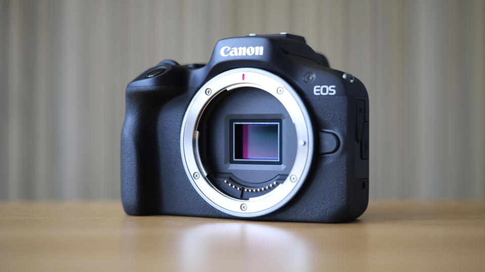 Canon EOS R100 camera on table with striped background