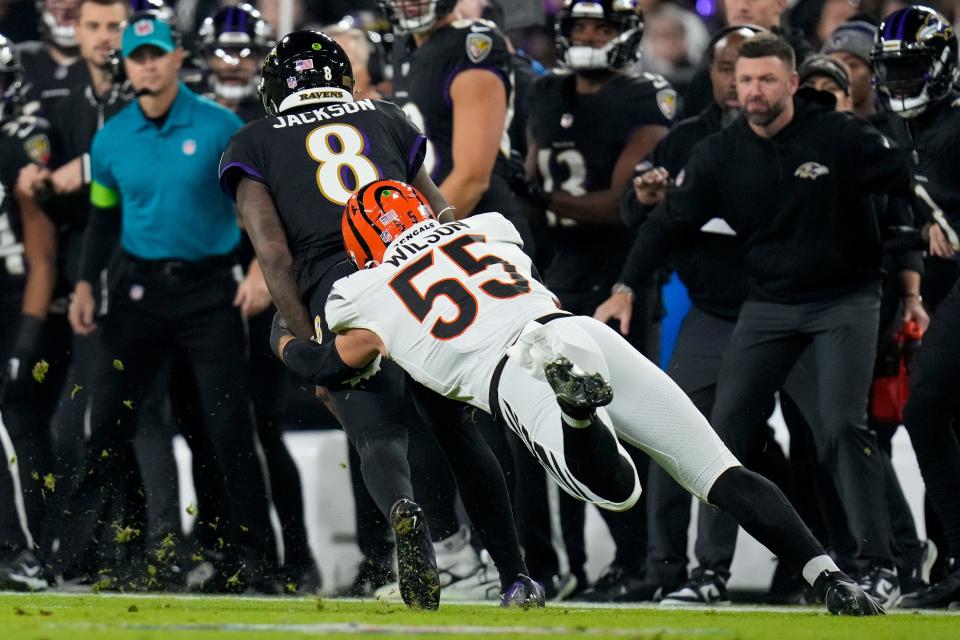 Baltimore Ravens quarterback Lamar Jackson is pulled down by Cincinnati Bengals linebacker Logan Wilson.