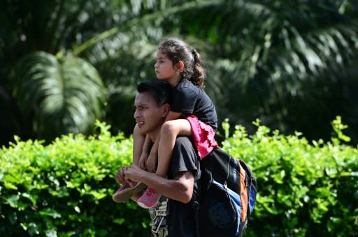 Honduran migrants walk on the road to Puerto Barrios in Guatemala after breaking through the border