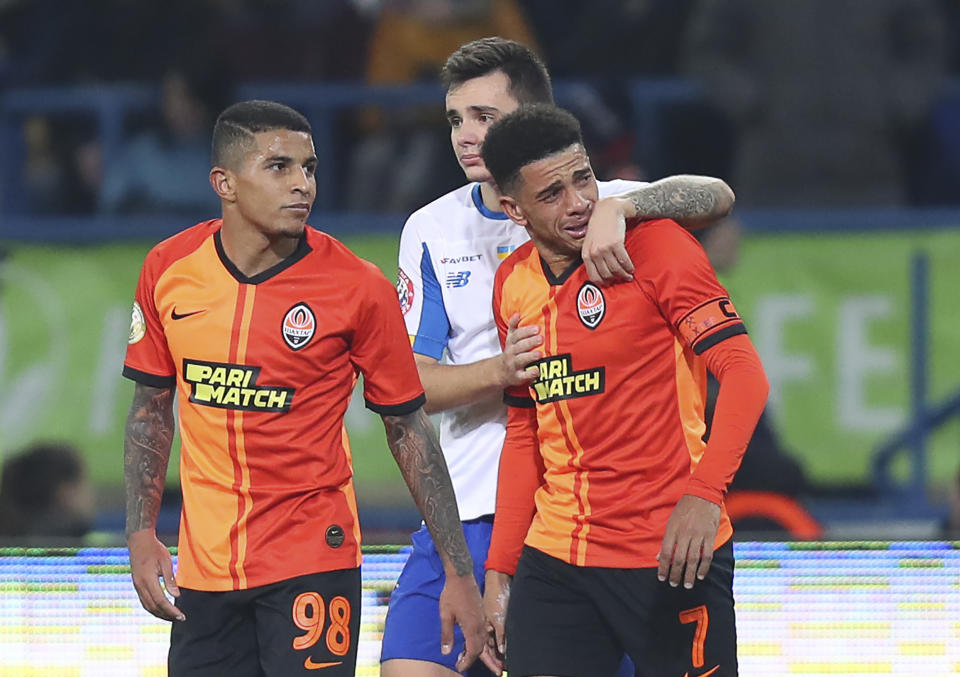 Shakhtar's Brazilian player Taison, right, reacts as he leaves the pitch after he was red-carded for his reaction on racial abuse, while Dynamo Kyiv Mykola Shaparenko, center, calmed him down, during Premier League soccer match in Kharkiv, Ukraine, on Sunday, Nov. 10, 2019. Shakhtar's Dodo, left, looks on. The Ukrainian Premier League on Monday called for an inquiry after a Brazilian player for Shakhtar Donetsk was sent off for responding to racist abuse with an obscene gesture. (AP Photo/Oleksandr Osipov)