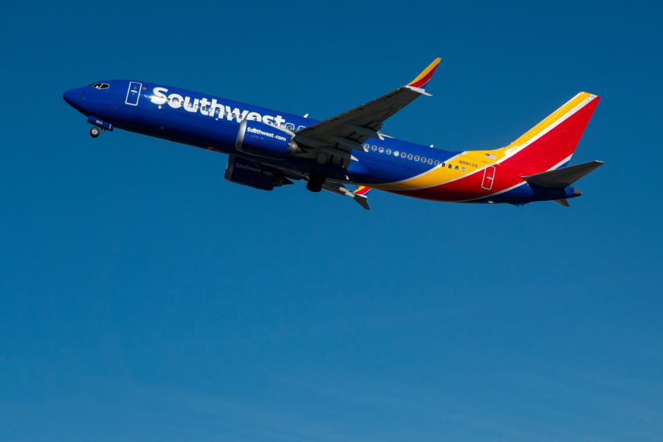 A Southwest Airlines Boeing 737 MAX 8 flies against a blue sky.