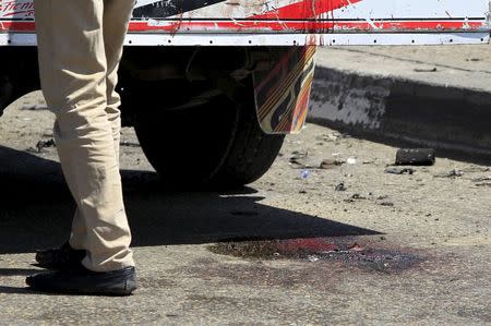 Bloodstains are seen on the ground as security officials inspect the scene of a car bomb blast on a bridge in the Cairo district of Zamalek, April 5, 2015. REUTERS/Mohamed Abd El Ghany