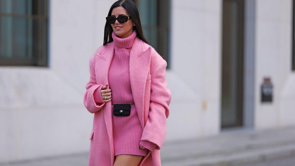 a woman wearing a pink coat and sunglasses