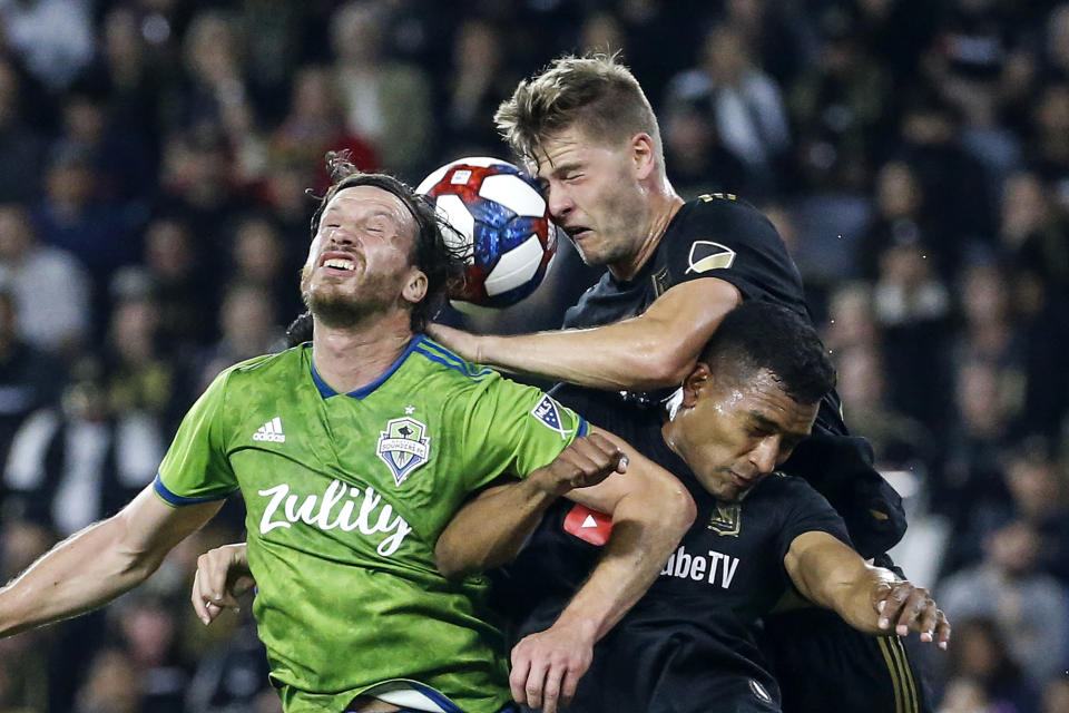 Seattle Sounders midfielder Gustav Svensson, left, vies for a head ball against Los Angeles FC defenders Walker Zimmerman, center, and Eddie Segura during the first half of the MLS soccer Western Conference final Tuesday, Oct. 29, 2019, in Los Angeles. (AP Photo/Ringo H.W. Chiu)