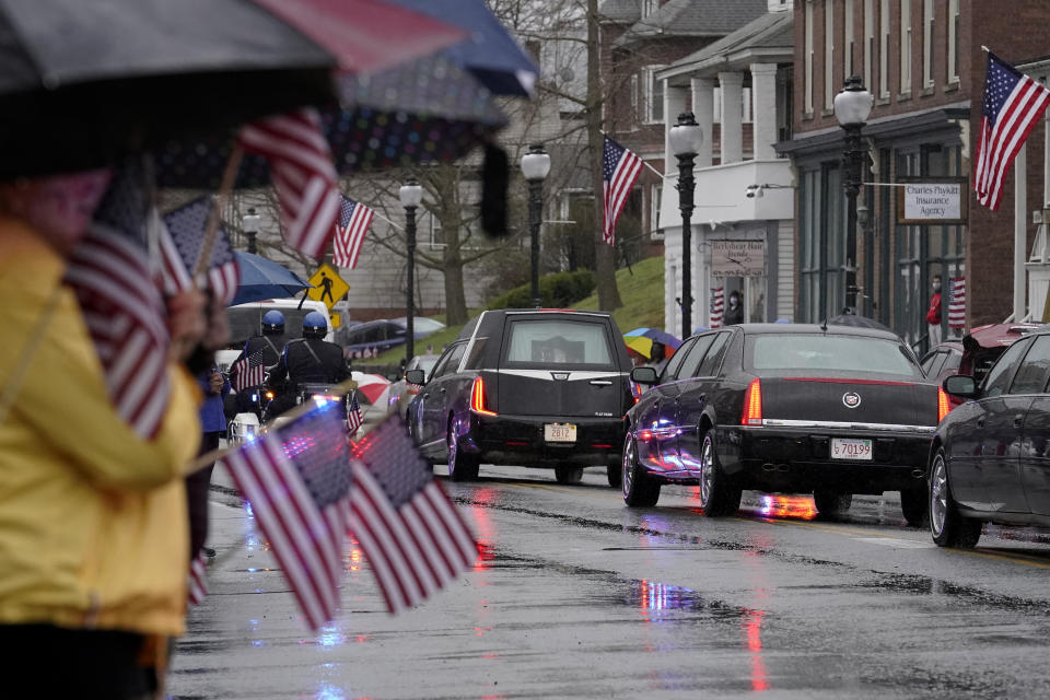 People display American flags as a hearse, center, carrying the coffin of the late U.S. Capitol Police officer William "Billy" Evans, left, drives though downtown Adams, Mass., following a funeral Mass for Evans, Thursday, April 15, 2021. Evans, a member of the U.S. Capitol Police, was killed on Friday, April 2, when a driver slammed his car into a checkpoint he was guarding at the Capitol. (AP Photo/Steven Senne)