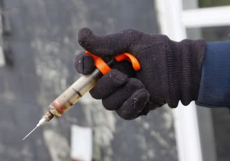 Hugh Byron, a retired dairy farmer, holds a syringe that he says he formerly used to treat his cows, outside his old dairy barn in Hillsboro, Kentucky November 13, 2014. REUTERS/John Sommers II