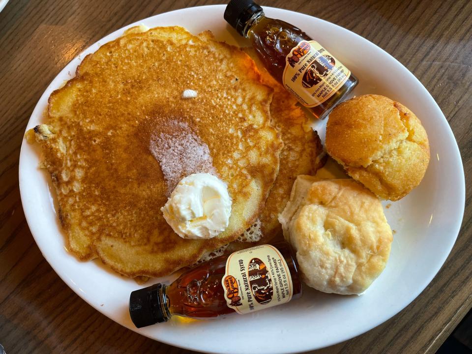 Plate of two pancakes, a biscuit, cornbread, and two containers of maple syrup