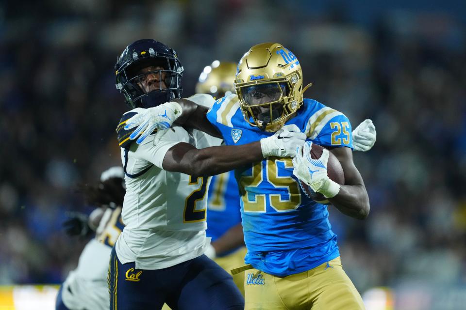 Nov 25, 2023; Pasadena, California, USA; UCLA Bruins running back TJ Harden (25) carries the ball against California Golden Bears defensive back Craig Woodson (2) in the first half at Rose Bowl. Mandatory Credit: Kirby Lee-USA TODAY Sports