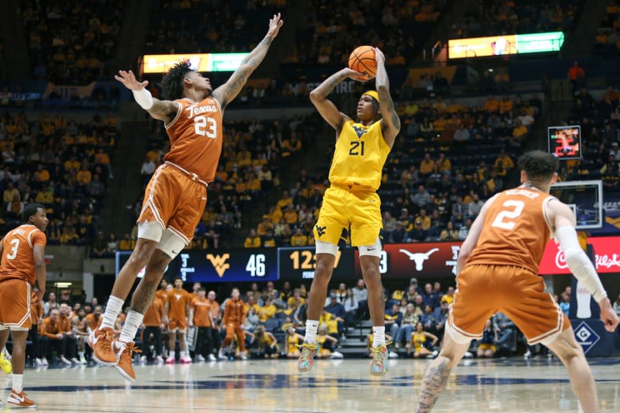 West Virginia guard RaeQuan Battle (21) is defended by Texas forward Dillon Mitchell (23) during the second half of an NCAA college basketball game on Saturday, Jan. 13, 2024, in Morgantown, W.Va. (AP Photo/Kathleen Batten)