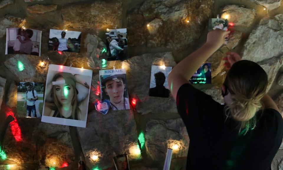 Attendees place photos of loved ones lost to addiction in a temporary memorial during an "Overdose Awareness" event at Banning Park Friday.