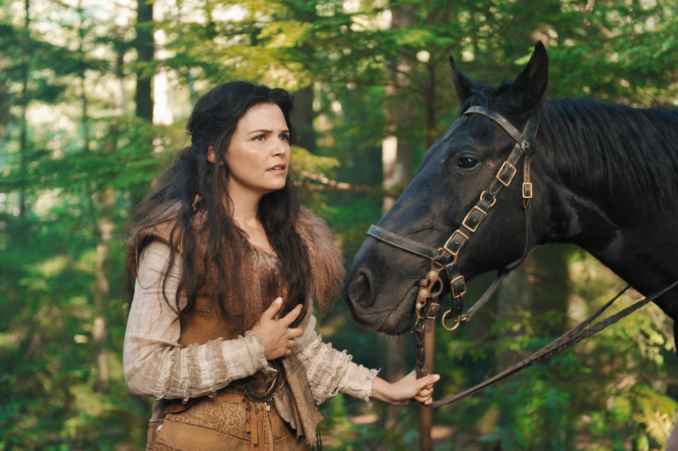 woman leading her horse in the woods