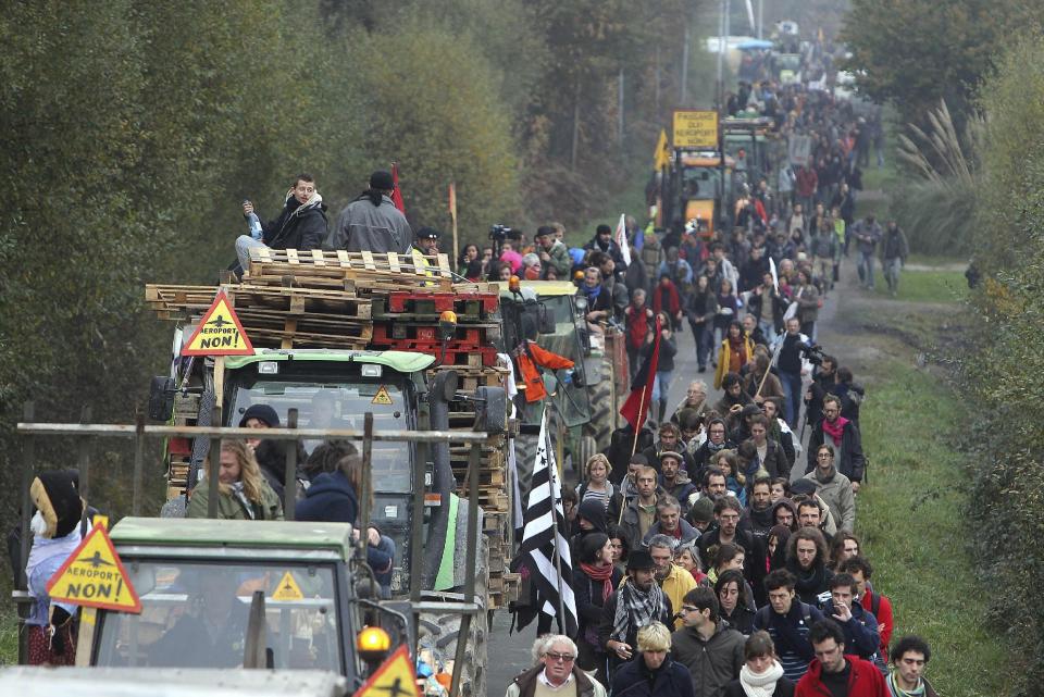 FILE - This Nov. 17, 2012 file photo shows demonstrators walking along a road near Notre Dame des Landes, western France, as part of a protest against a project to build an international airport, in Notre Dame des Landes, near Nantes. An unlikely alliance of anarchists and beret-wearing farmers is creating a headache for President Francois Hollande’s beleaguered government by mounting an escalating Occupy Wall Street-style battle that has delayed construction on the ambitious airport near the city of Nantes for months. (AP Photo/David Vincent, File)